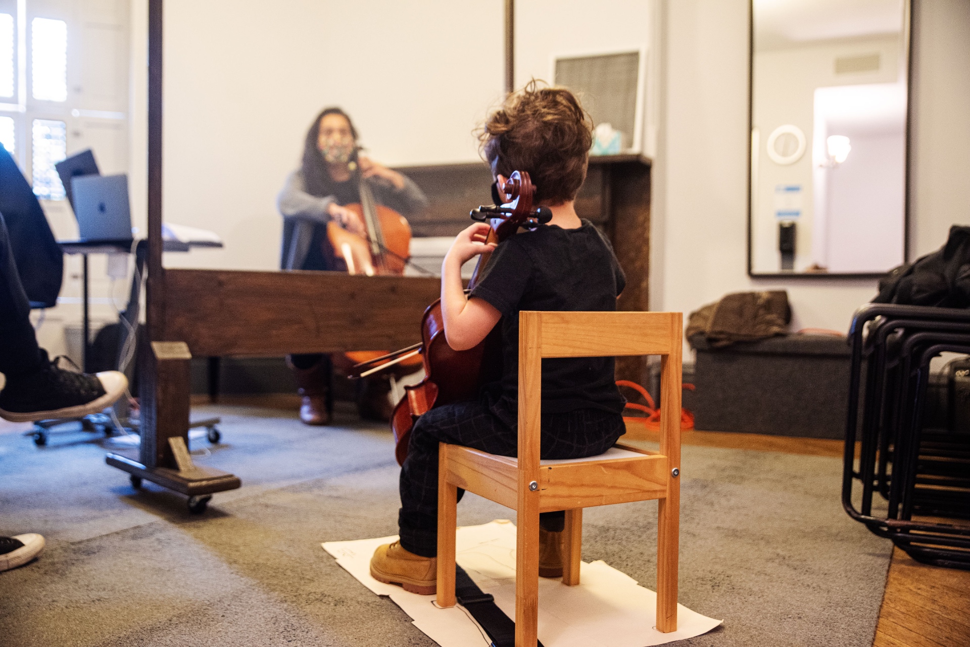 Child practicing cello in front of a mirror